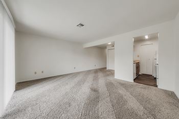 A large, empty room with a carpeted floor and white walls